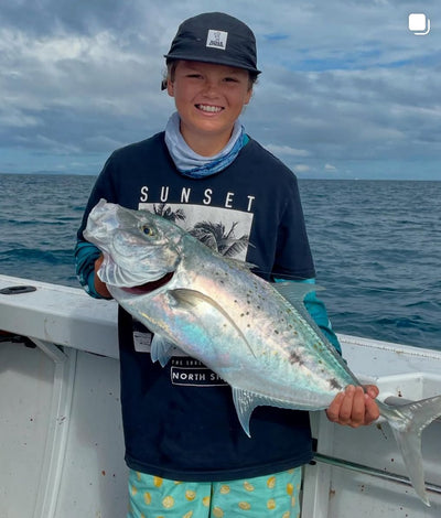 Person holding a large fish on a boat with ocean and sky in the background wearing 5 Panel Cap.